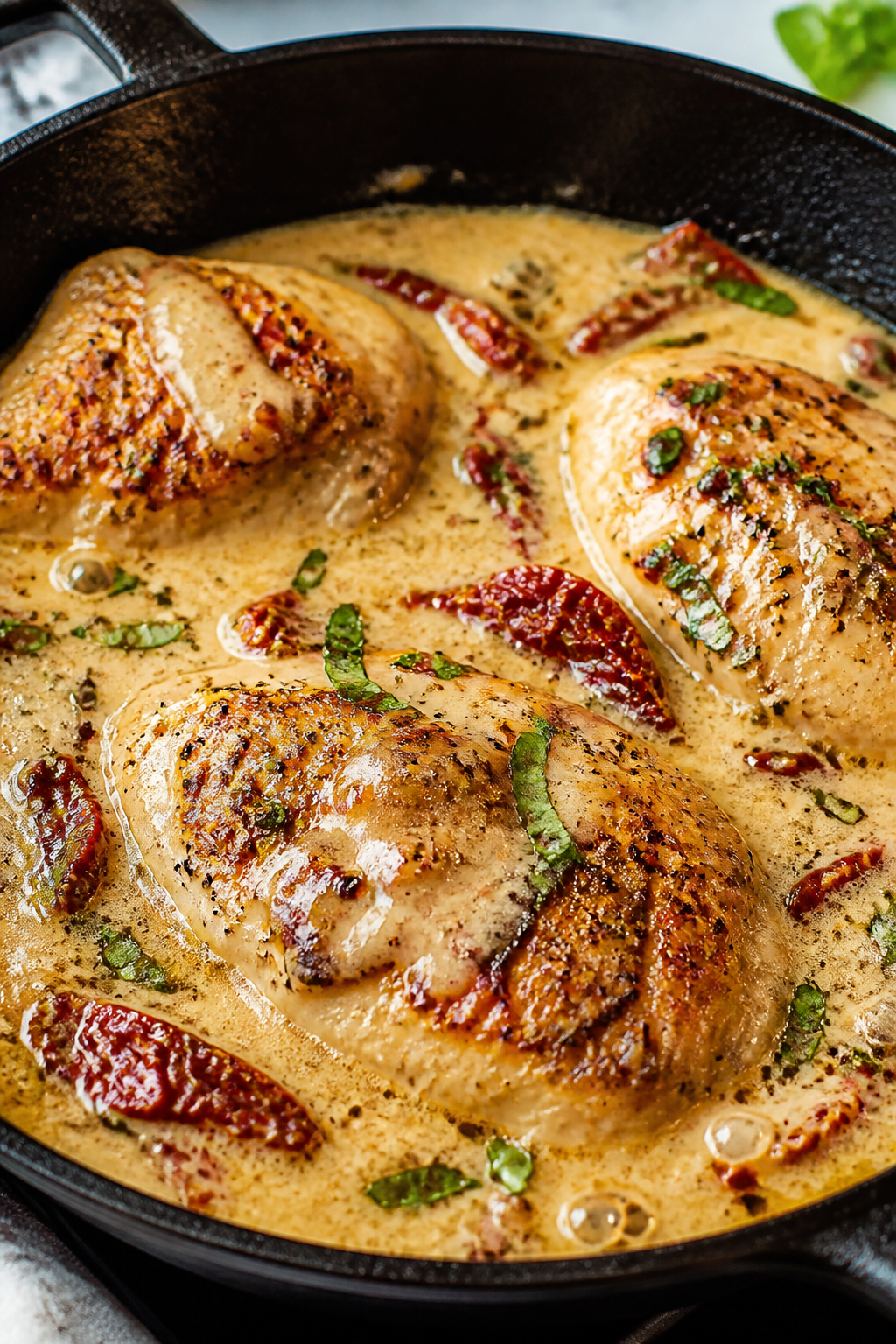 Close-up detail: Golden-seared chicken breasts nestled in a simmering creamy garlic-Parmesan sauce w