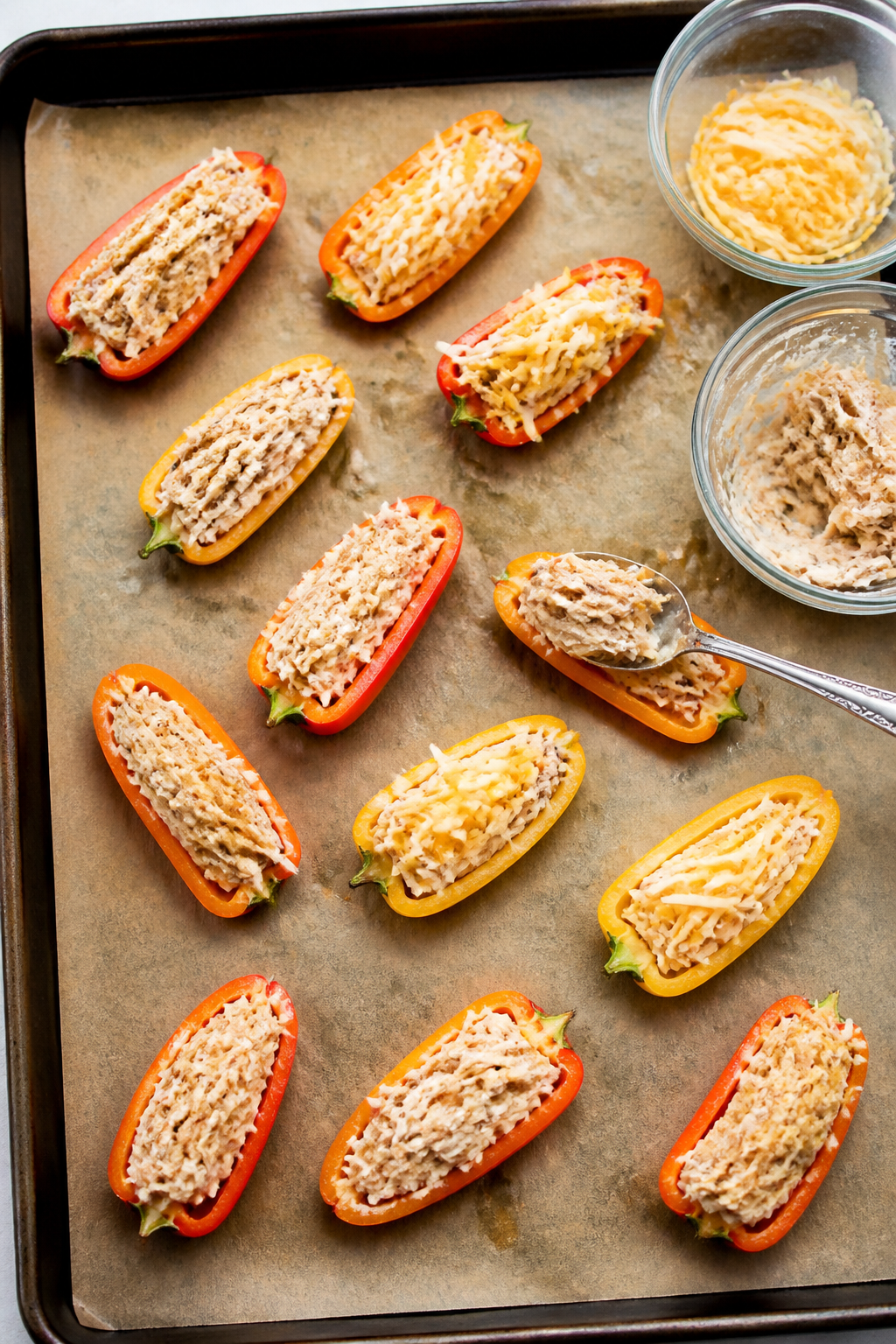 Cooking process: Overhead shot of halved mini sweet peppers arranged cut-side up on a parchment-line