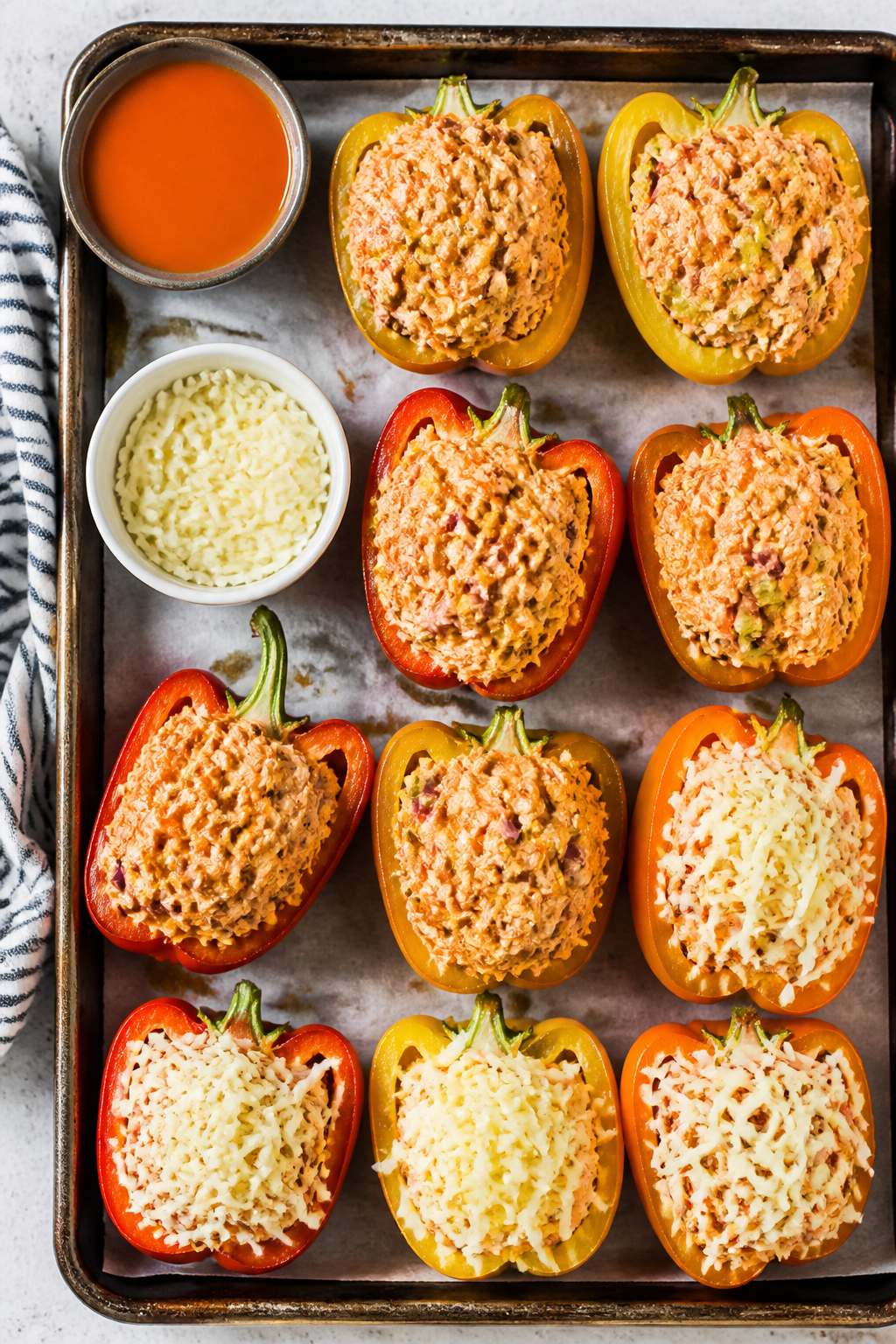 Cooking process: Overhead shot of par-baked bell pepper halves being filled and mounded with creamy 