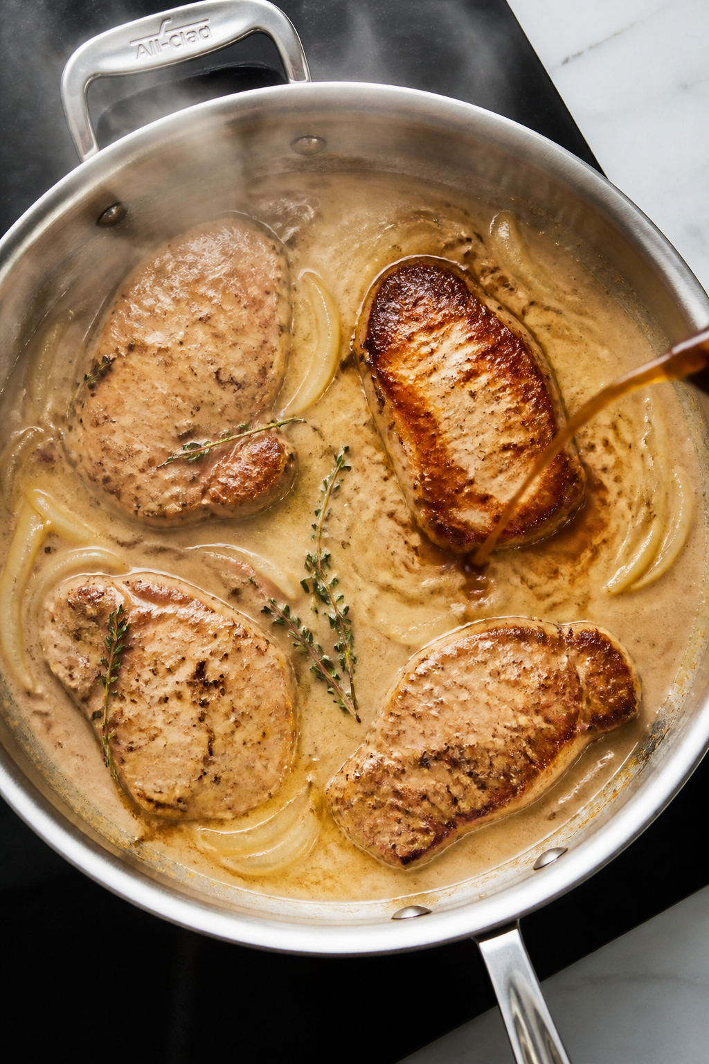 Cooking process: Overhead shot of pork chops simmering gently in creamy chicken-broth-and-milk gravy