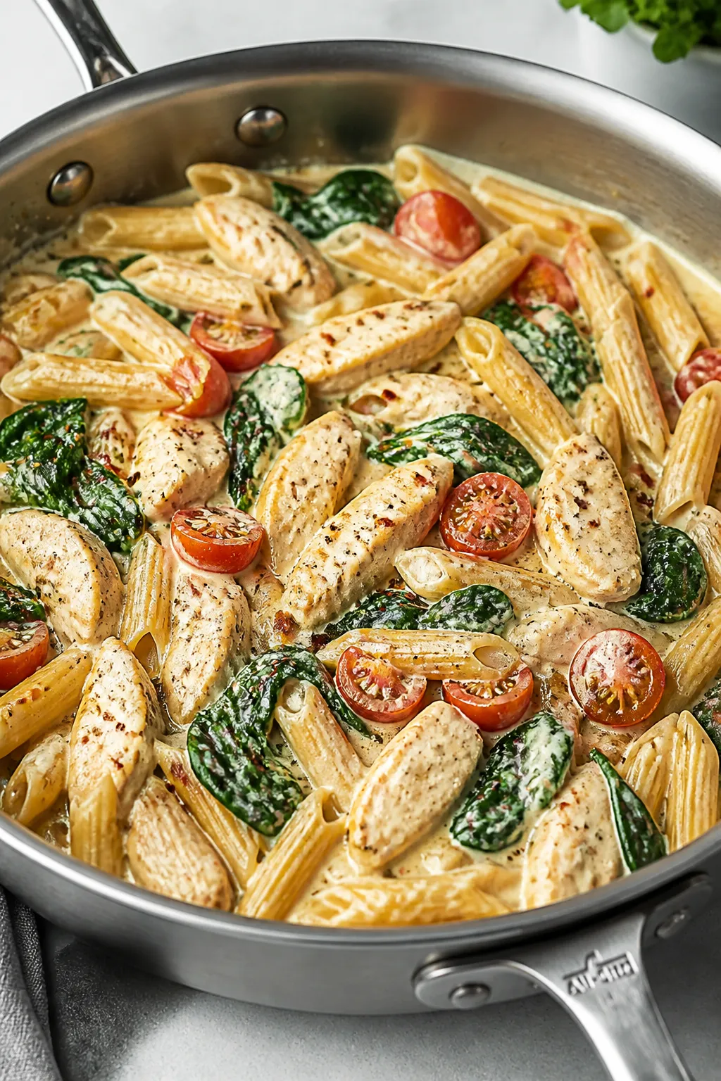 Cooking process: Creamy Greek yogurt–Parmesan sauce being folded into al dente whole wheat penne w