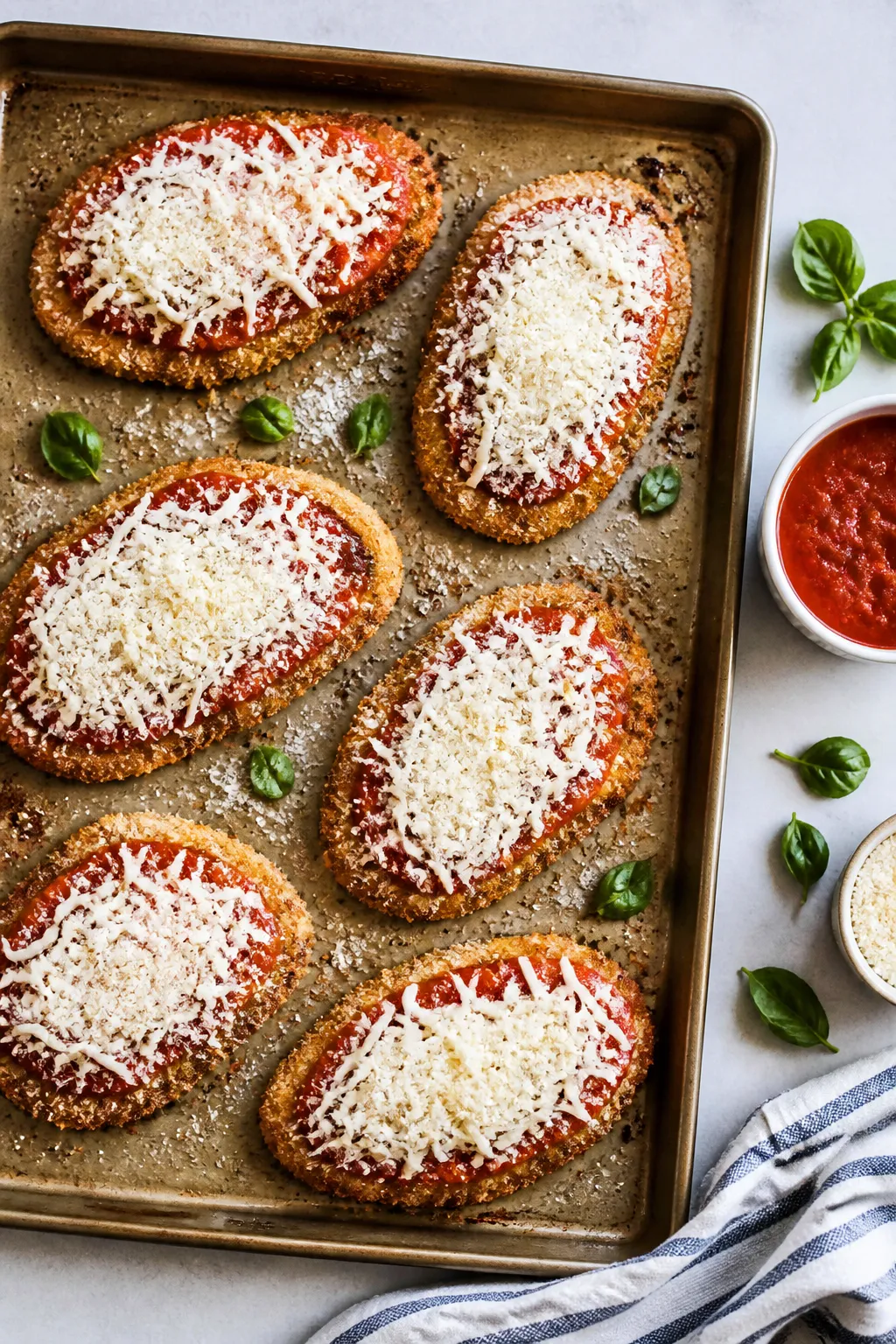 Cooking process: Overhead shot of assembled Healthy Chicken Parmesan on a baking sheet mid-step—ea