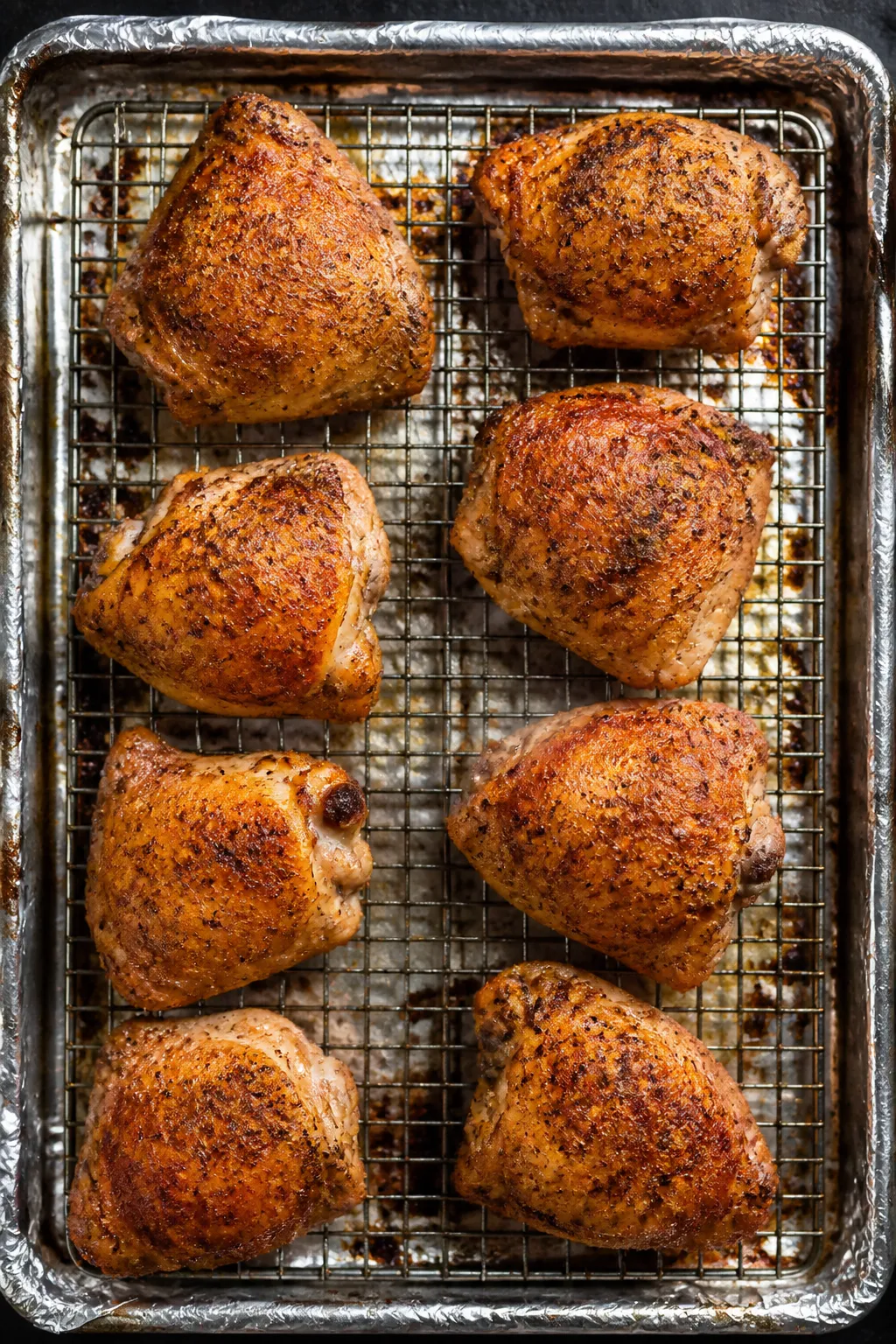 Cooking process: Overhead shot of seasoned, oil-kissed chicken thighs arranged skin-side up on a pre