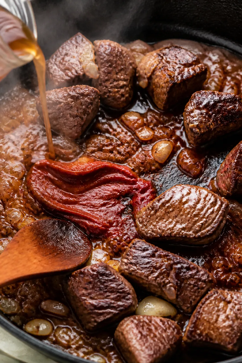 Cooking process — Searing for flavor: Close-up of browned beef chuck cubes sizzling in a heavy ski