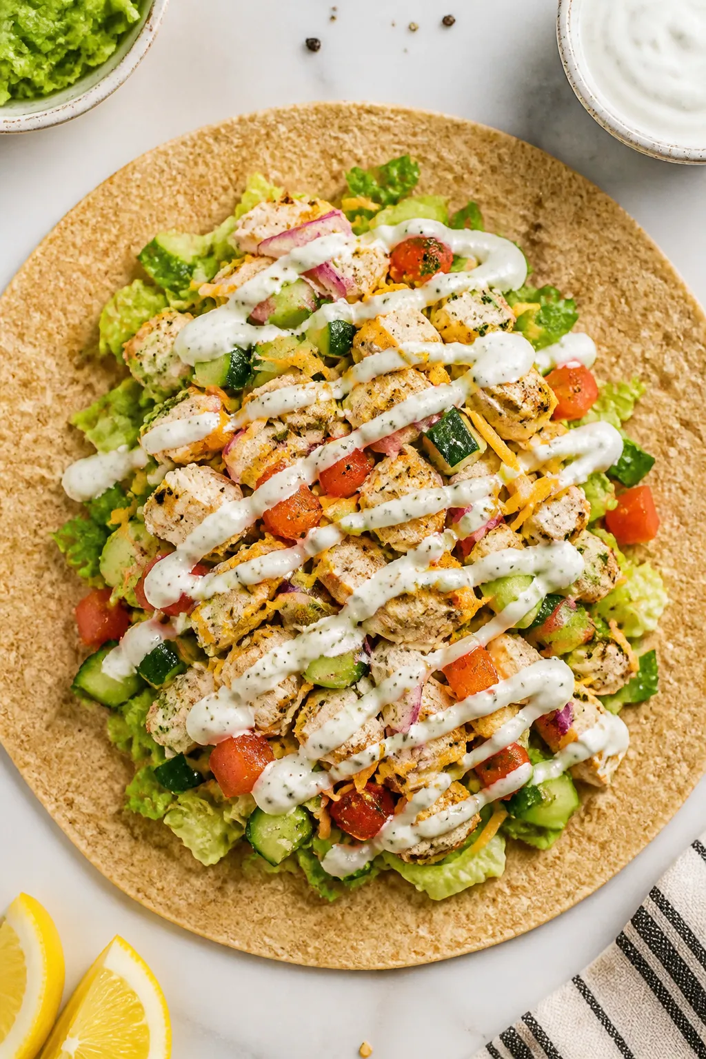 Overhead shot of a High Protein Ranch Chicken Wrap mid-assembly on a warm whole-wheat tortilla: neat